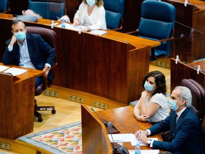 Alberto Reyero observa a Isabel Díaz Ayuso y Enrique Ruiz-Escudero, durante un pleno de la Asamblea.