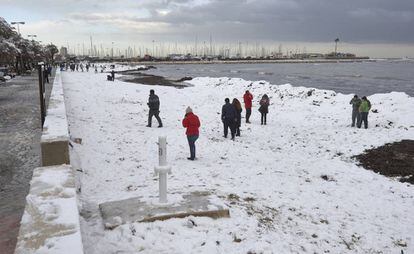 Vecinos de Denia visitan la playa de La Marineta tras las intensas nevadas.