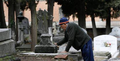 Urbano, de 78 a&ntilde;os, limpia una l&aacute;pida en el cementerio de la Almudena de Madrid.