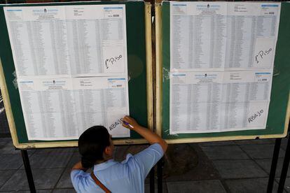 Un oficial de policía realiza anotaciones en un listado con el registro nacional de electores en un colegio electoral en Buenos Aires.