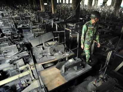 Un polic&iacute;a inspecciona unos talleres de confecci&oacute;n de ropa tras incendiarse en Dacca (Bangladesh), el pasado noviembre.