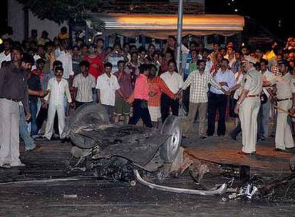 Curiosos observan los restos de un coche destruido tras la serie de explosiones y tiroteos en el sur de Bombay.