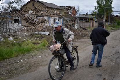 Un residente en la región de Zaporiyia se mueve con su bici entre los restos de casas dañadas tras un ataque ruso el 10 de mayo. 