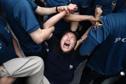 A young protester is detained by police officers after trying to enter the Japanese embassy in Seoul in a protest against the dumping of contaminated water from Fukushima.
