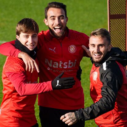 GIRONA, 09/12/2023.- El defensa del Girona Eric (c) abraza a sus compañeros Pablo Torre (i) y Aleix García durante entrenamiento del equipo este sábado en el centro de entrenamiento La Viña de Girona.  El Girona se enfrenta mañana al FC Barcelona en un partido de LaLiga. EFE/David Borrat
