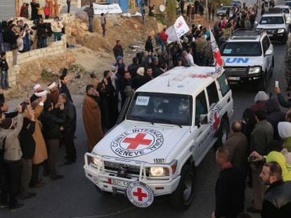 Un grupo de sirios tras cruzar el paso fronterizo liban&eacute;s de Masnaa este lunes en un convoy de la Cruz Roja y la ONU.