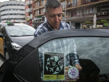 Un taxista col·loca al seu vehicle un adhesiu de la campanya violeta.