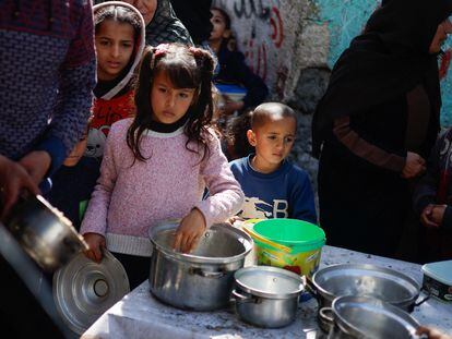 Unos niños palestinos esperan a recibir comida de una organización benéfica este martes, mientras hay  escasez de alimentos, en Rafah.