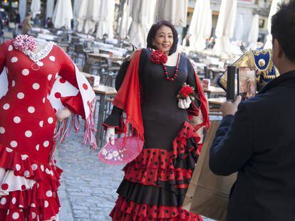 Una turista se fotografía con un traje de flamenca, en la Plaza de Mayor de Madrid. 