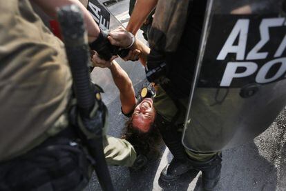 Policías arrastran a un detenido durante las protestas contra Merkel.