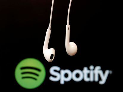 Auriculares en primer plano sobre el logotipo de Spotify. 
