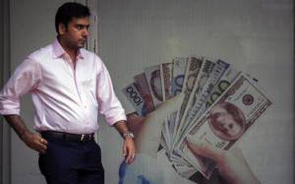 Un hombre pasa junto a un cartel anunciador de un establecimiento de cambio de divisas en Bombay, India. EFE/Archivo