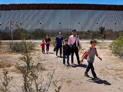 Una familia de migrantes guatemaltecos camina junto al muro fronterizo entre México y Estados Unidos, cerca de la población de Lukeville (EE UU), en agosto de 2023.