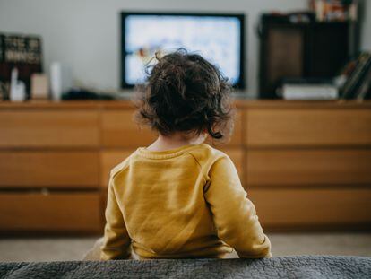 Una niña ve la televisión tradicional en casa.