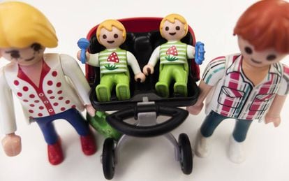 Unos padres múltiples pasean a sus bebés en su carrito gemelar, de Playmobil.