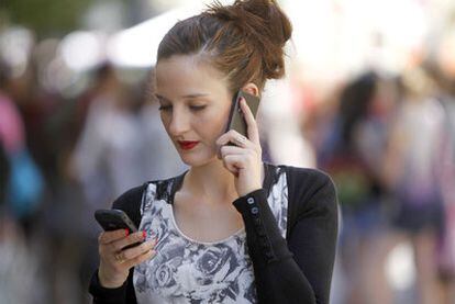 Una joven se comunica por dos teléfonos móviles al mismo tiempo en una calle de Madrid.