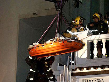 Los bomberos evacuan a un vecino cercado por el fuego (arriba).