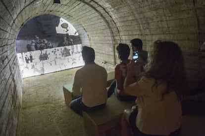 Visitantes del refugio de Castellón ante uno de los documentales que se proyectan en el interior.