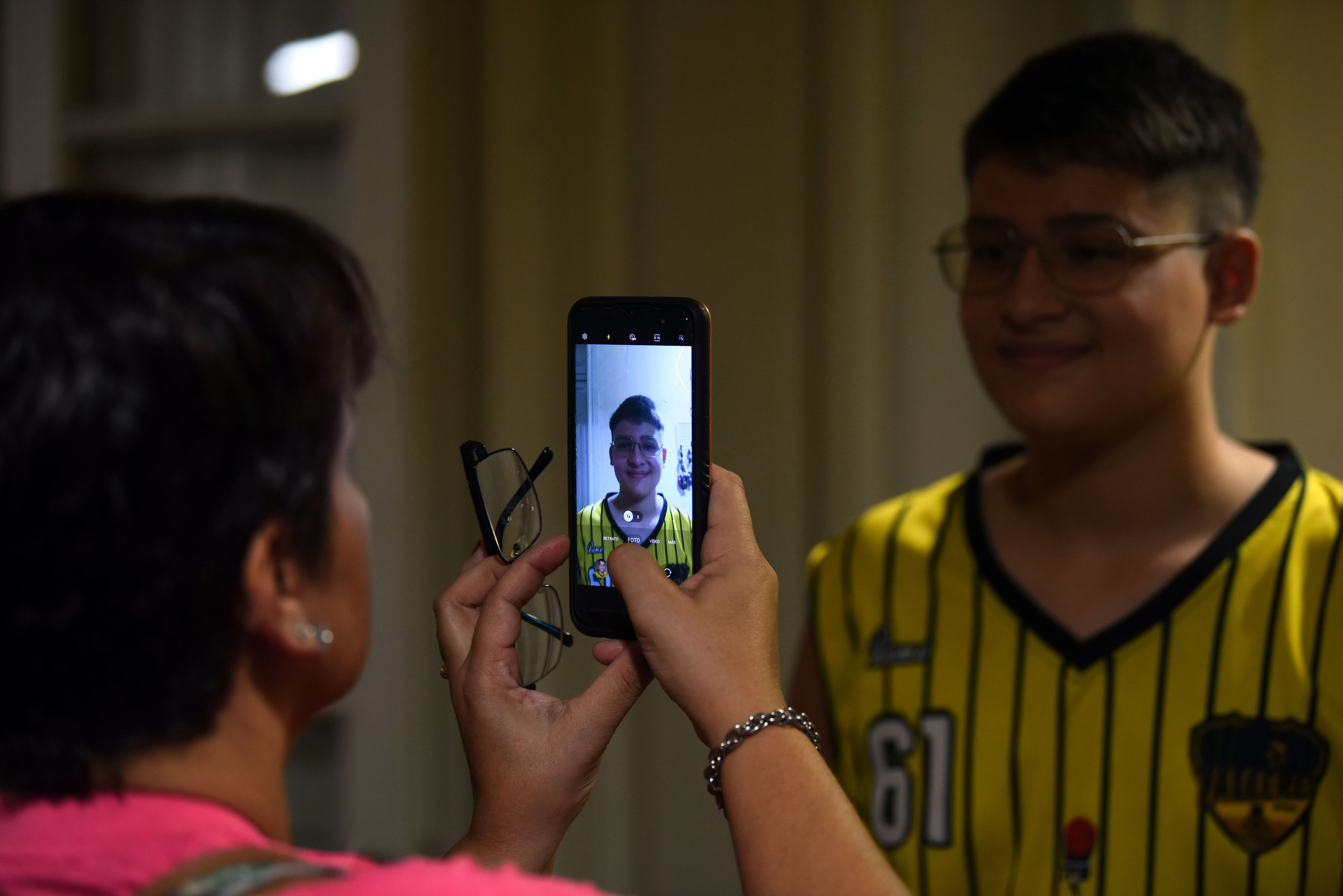 Una mujer saca una fotografía a su hijo portando su nuevo par de anteojos.