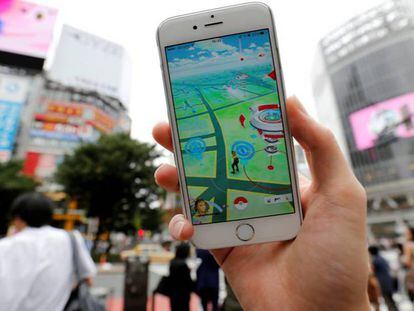 Un hombre juega a Pokémon Go con su móvil en una concurrida calle de Tokio.