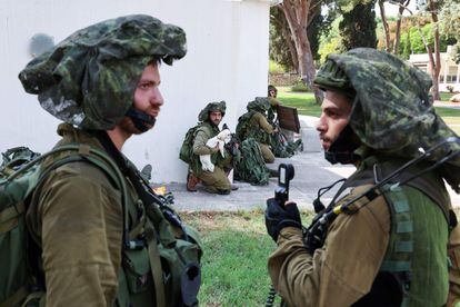 Un soldado israelí sostiene un perro mientras su unidad toma posición en el kibutz de Kfar Aza, en el sur de Israel, colindante con la franja de Gaza. 