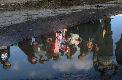 Reflejo de unos niños sirios en un charco de agua mientras miran cómo un convoy de las Naciones Unidas y la Media Luna Roja de Siria reparten ayuda en Utaya, enclave rebelde de Ghuta Oriental (Siria).