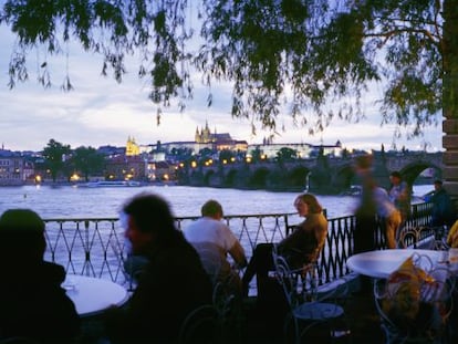 Una terraza junto al río Moldava, en Praga, con el puente de Carlos al fondo.