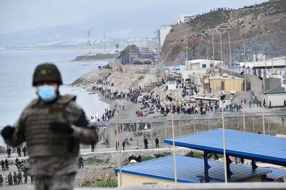 Decenas de marroquíes aguardan ante el espigón que limita la frontera de Marruecos con España en Ceuta.