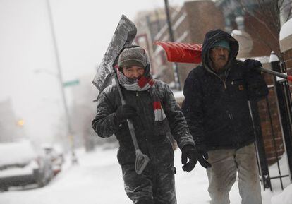 Dos hombres llevan palas para limpiar la nieve en Detroit.