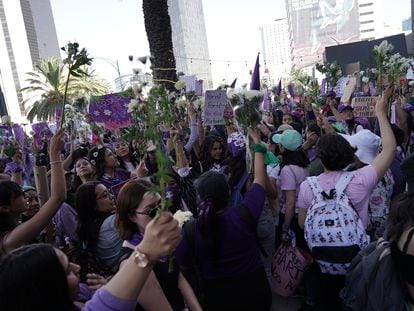 Mujeres llevan flores durante la marcha por el 8M en Ciudad de México.