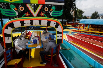 Médicos examinan a un hombre para detectar COVID-19 a bordo de una "trajinera" en  la alcaldía Xochimilco en la Ciudad de México, México.