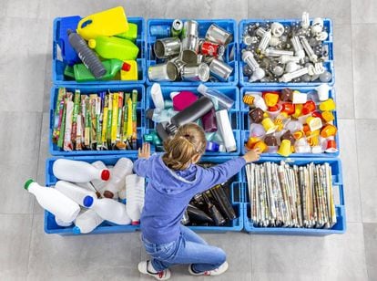 Una niña separa diferentes residuos colocándolos en sus correspondientes espacios.