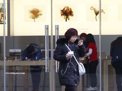 Una joven china junto a una tienda de Apple en Pek&iacute;n (China).