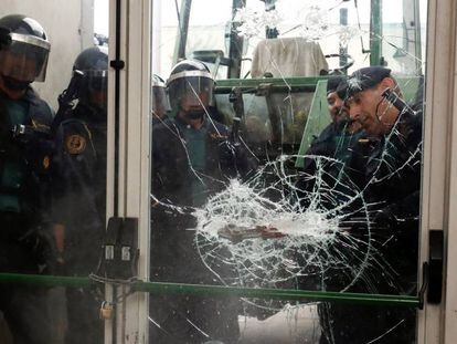 Oficiales de la Guardia Civil rompen una puerta de cristal en un punto de votación del referéndum ilegal de independencia.