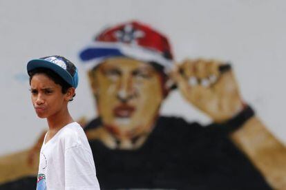 Un joven del barrio caraqueño de Petare delante de un grafiti de Hugo Chávez, ataviado con indumentaria de rapero.