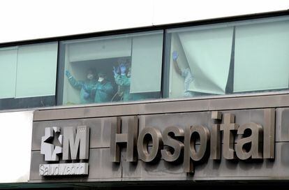 El personal sanitario saluda desde el interior del Hospital de La Paz, en Madrid, este miércoles.