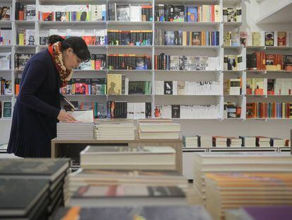 Una mujer hojea un libro en una librer&iacute;a de Barcelona.