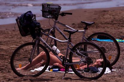 Dos jóvenes toman el sol entre dos bicicletas en la playa de la Misericordia de Málaga, provincia que ha pasado a la fase 2 de la desescalada, en la que se permite el baño en mitad del estado de alarma ocasionado por al crisis sanitaria del coronavirus.
