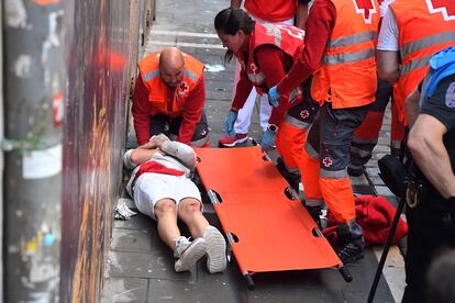 Un corredor es asistido por personal de la Cruz Roja. Seis personas han sido trasladadas a centros hospitalarios, dos de ellas por asta de toro, tras el tercer encierro de San Fermín.