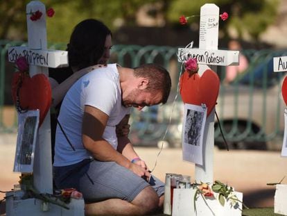 Amigos de una de las víctimas de la matanza de Las Vegas, junto a una cruz en su honor.