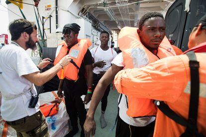Miembros de la embarcación colocan chalecos salvavidas a varios migrantes.