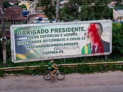 Una cartelera con una pintada sobre la imagen de Bolsonaro