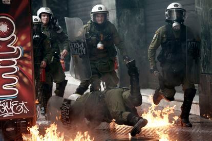 Un policía cae al suelo durante los incidentes con un grupo radical en las calles de Atenas (Grecia).