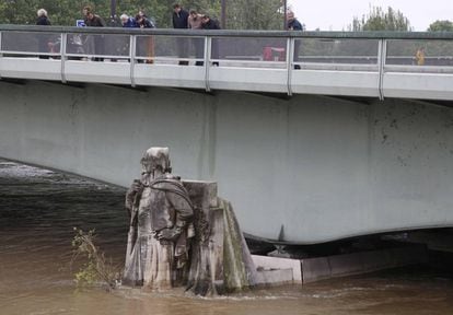 Parisienses observando una estatua del Pont de l'Alma, cubierta por el agua del Sena.