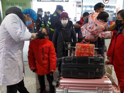Un médico toma la temperatura a los viajeros antes de embarcar en el aeropuerto chino de Changsha, este lunes. En vídeo, las declaraciones de la ministra de Sanidad de Baviera.