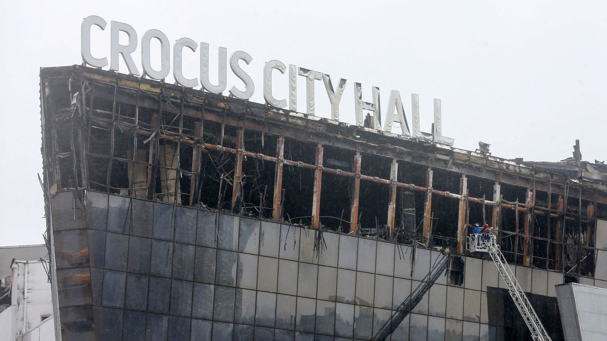 Personal de emergencias trabajan con una grúa en el exterior de la sala de conciertos Crocus, este sábado. 