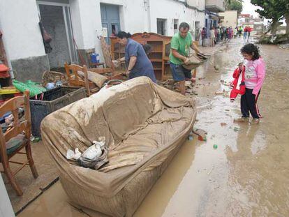 Vecinos de El Verger (Alicante) sacan los muebles de su casa, inundada por la crecida del río Girona.