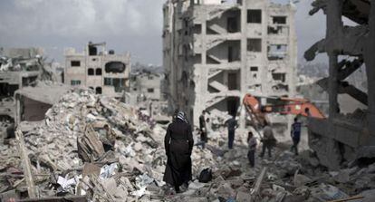 Una mujer palestina camina entre los escombros de las casas en Gaza.