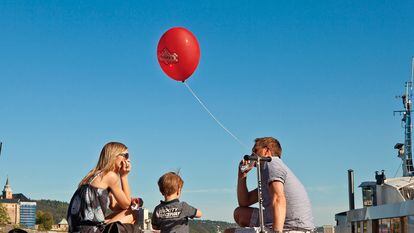 Una familia, en el puerto de Oslo con un globo sujeto a un patinete.