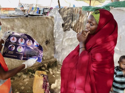 Una mujer residente en el campo de desplazados internos de Weydow, cerca de Mogadiscio (Somalia)  es informada por un trabajador humanitario sobre cómo protegerse para evitar contagiarse de covid-19 el 10 de junio de 2020.